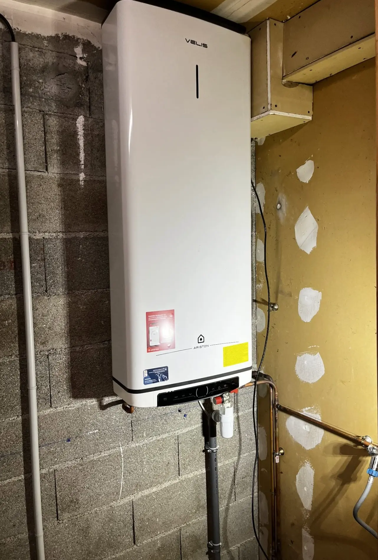 Chauffe-eau électrique neuf fixé sur un mur en agglos